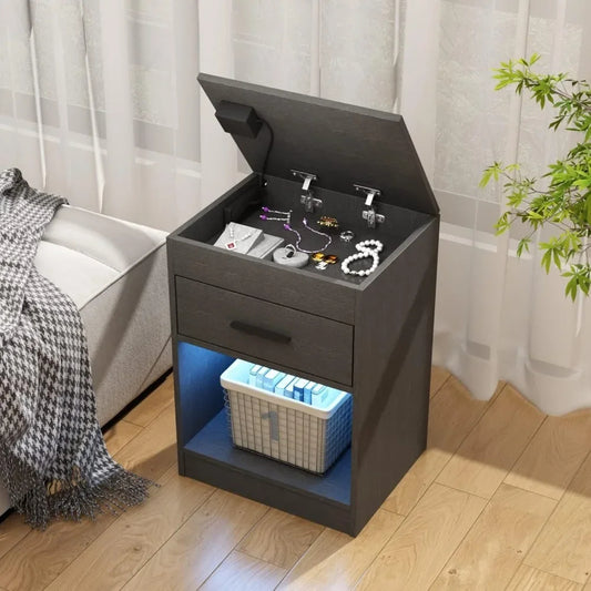 Black nightstand with open top displaying jewelry, drawer, and blue illuminated bottom shelf in a bedroom setting.