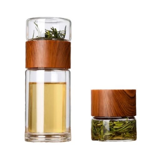 Two glass containers with wooden lids, one filled with tea leaves and the other with a clear liquid.