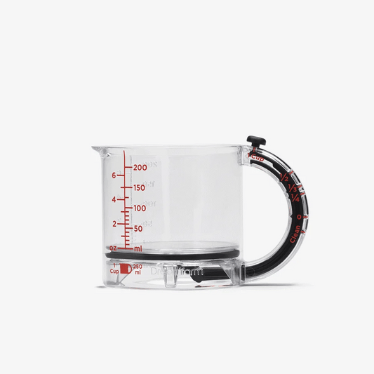 Clear measuring cup with black handle and red measurement markings on a white background